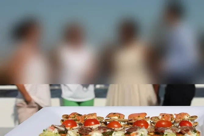 A tray of canapés with smoked salmon and tomato on a boat deck, guests with drinks blurred behind