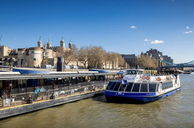 A City Cruises boat moored at Tower Millennium Pier below the Tower of London on a sunny day